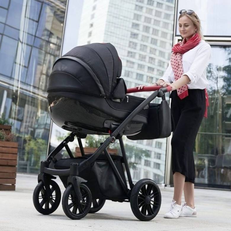 Czy czarny wózek blaknie i nagrzewa się – kobieta prezentuje czarną gondolę dziecięcą.